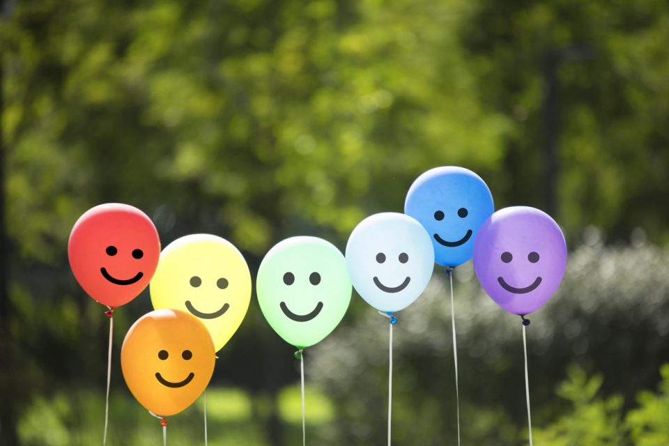 Cluster of multi-color balloons with smiling faces drawn on