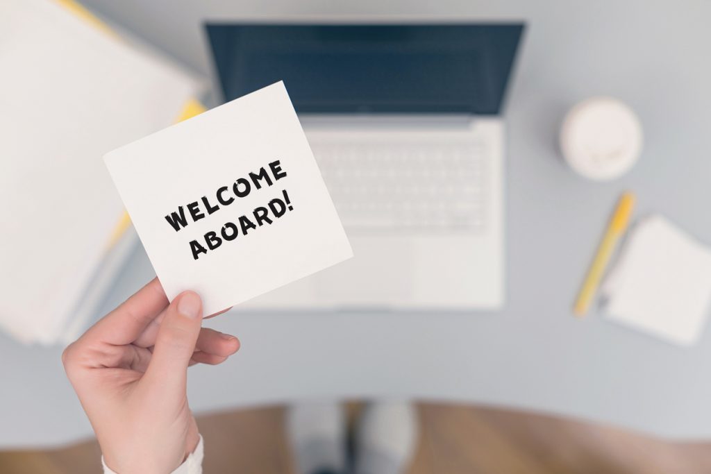 Woman clerk sitting holding note paper sticker with welcome aboard phrase. Business concept. Concept.