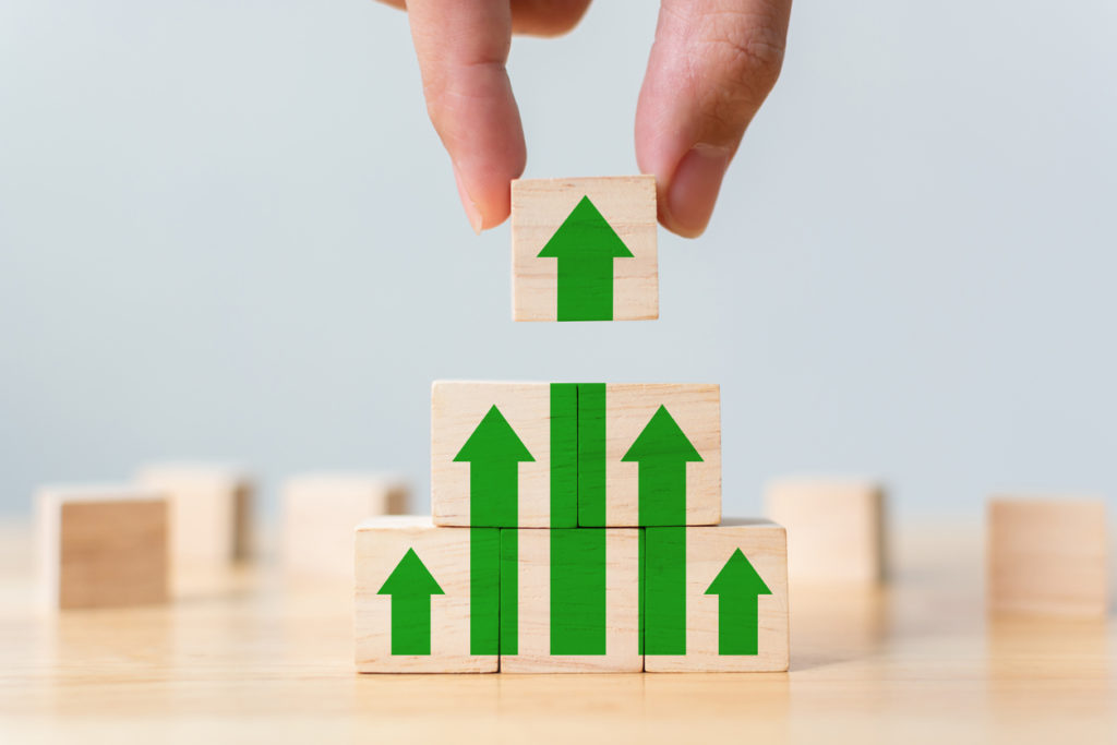 Ladder career path for business growth success process concept. Wood block stacking as step stair with arrow up. Hand putting wooden cube block on top pyramid