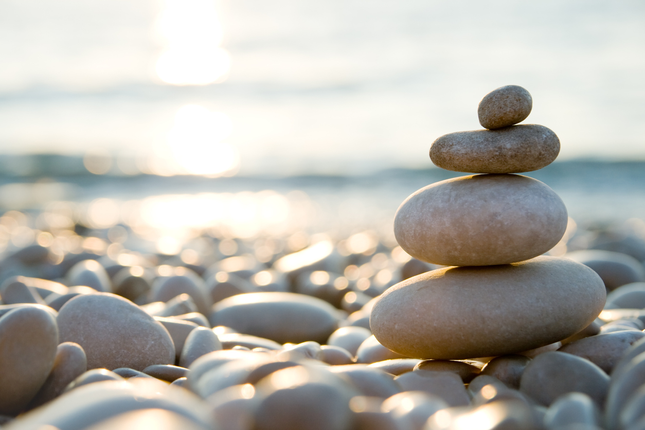 Balanced stones on a pebble beach during sunset.