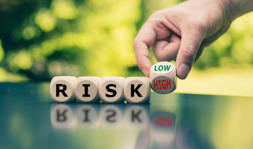 Symbol for reducing a risk. Cubes form the word "RISK" while a hand turns a cube and changes the word "high" to low" (or vice versa).