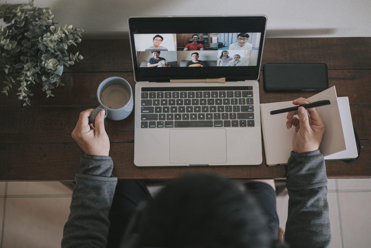 An asian chinese male working at home using laptop video conference call meeting with headset